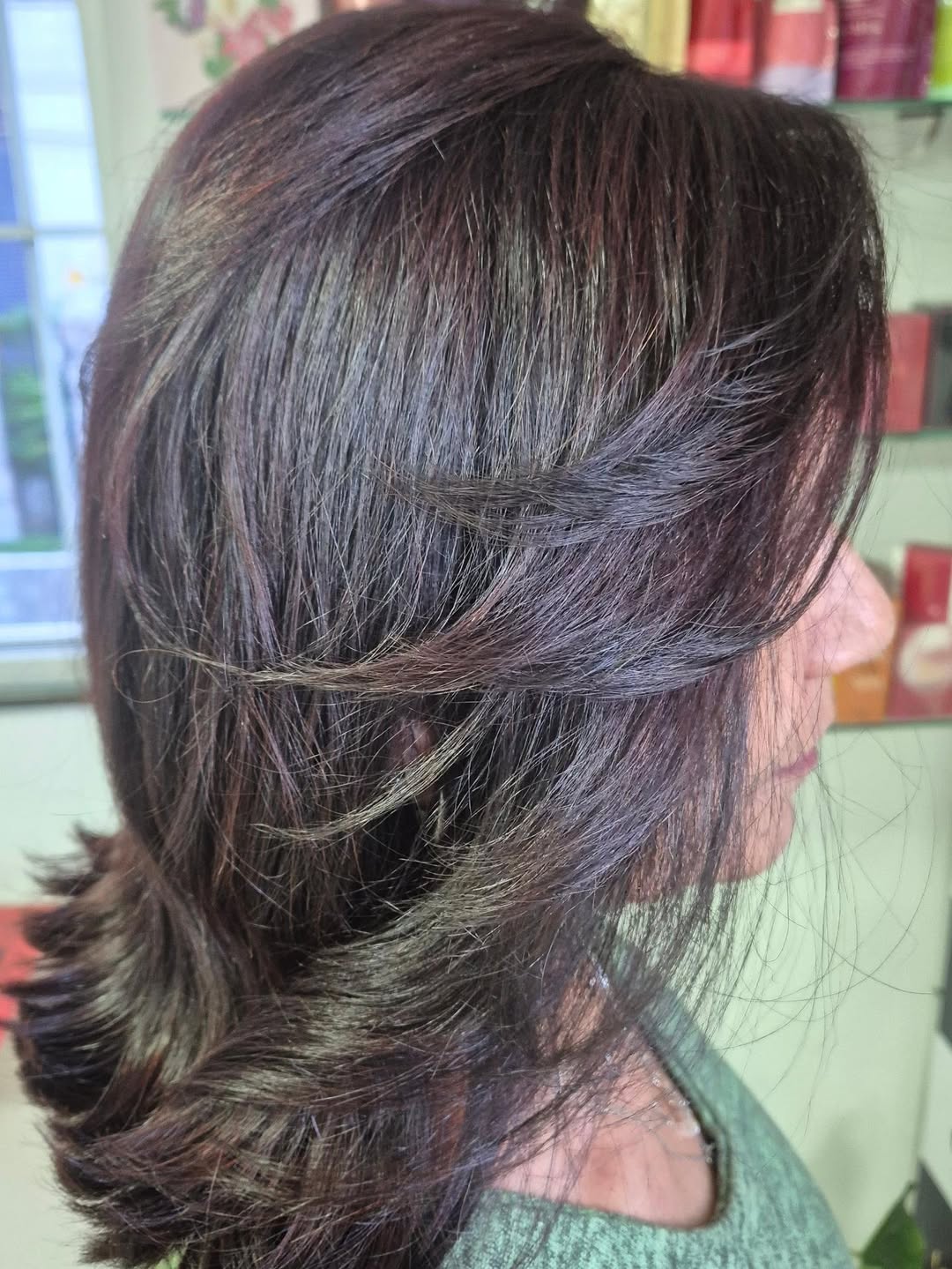 Corte em camadas com iluminação suave em cabelos castanhos, visto de lado no Salão Top Model.